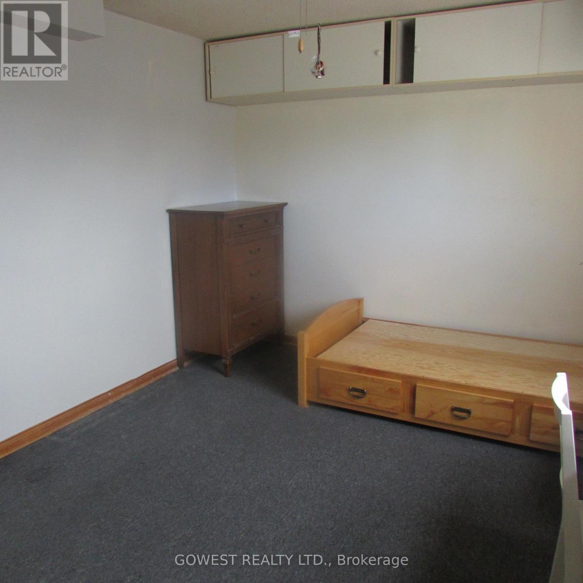 A bedroom with a bed, dresser and wardrobe.