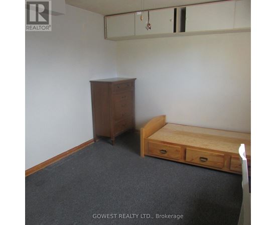 A bedroom with a bed, dresser and wardrobe.