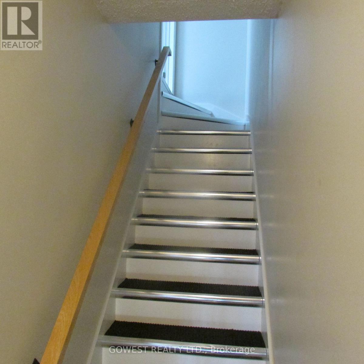 A staircase with a wooden handrail and metal steps.