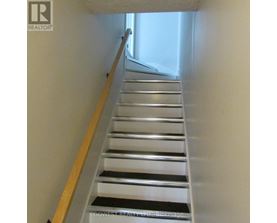A staircase with a wooden handrail and metal steps.