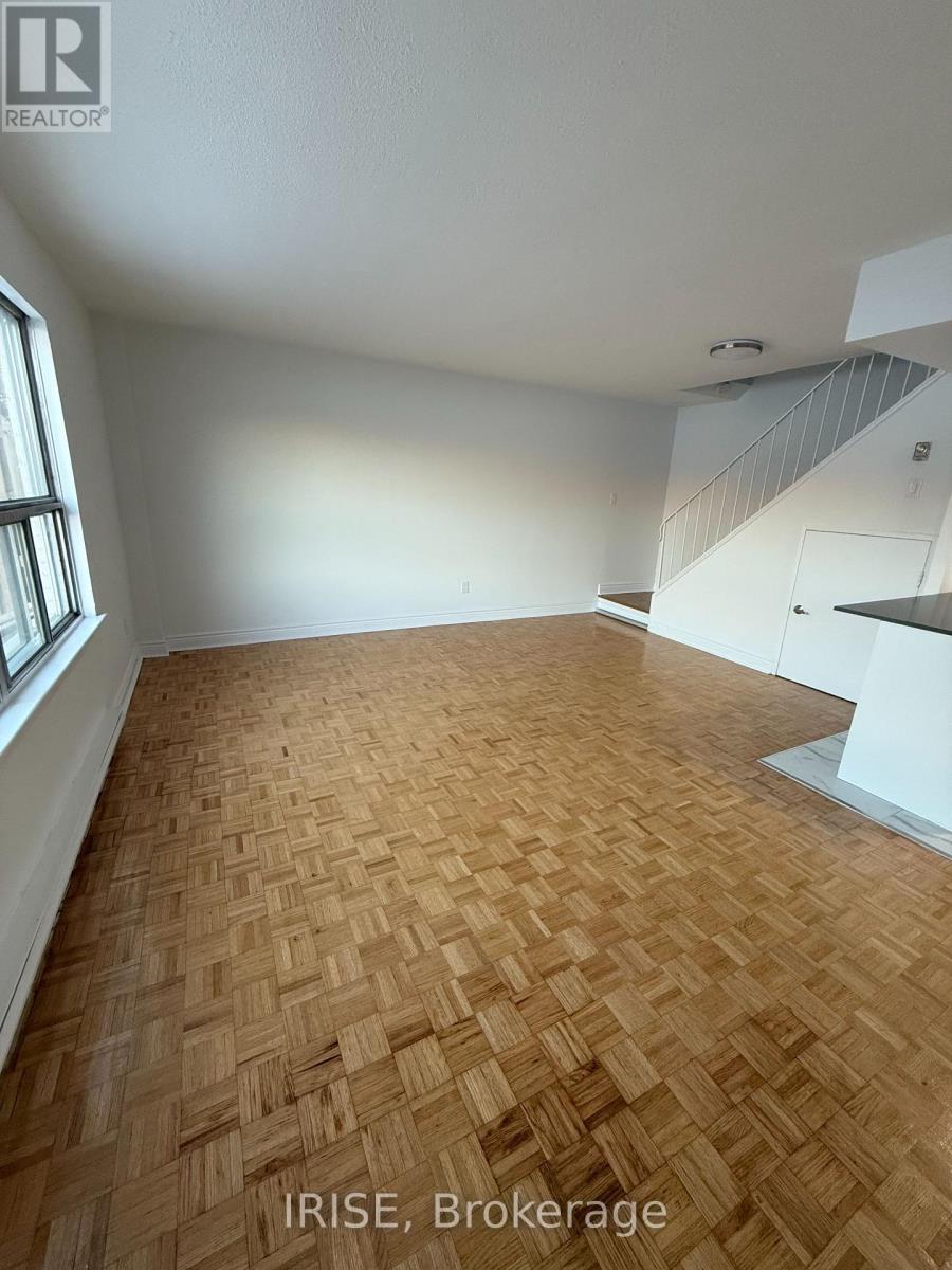 A room with wooden flooring and white walls, labeled "IRISE, Brokerage".