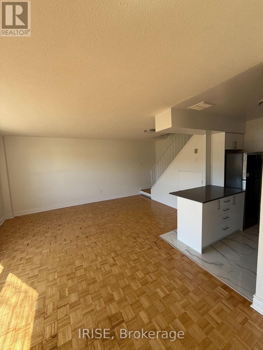 A room with a kitchen area and a staircase.