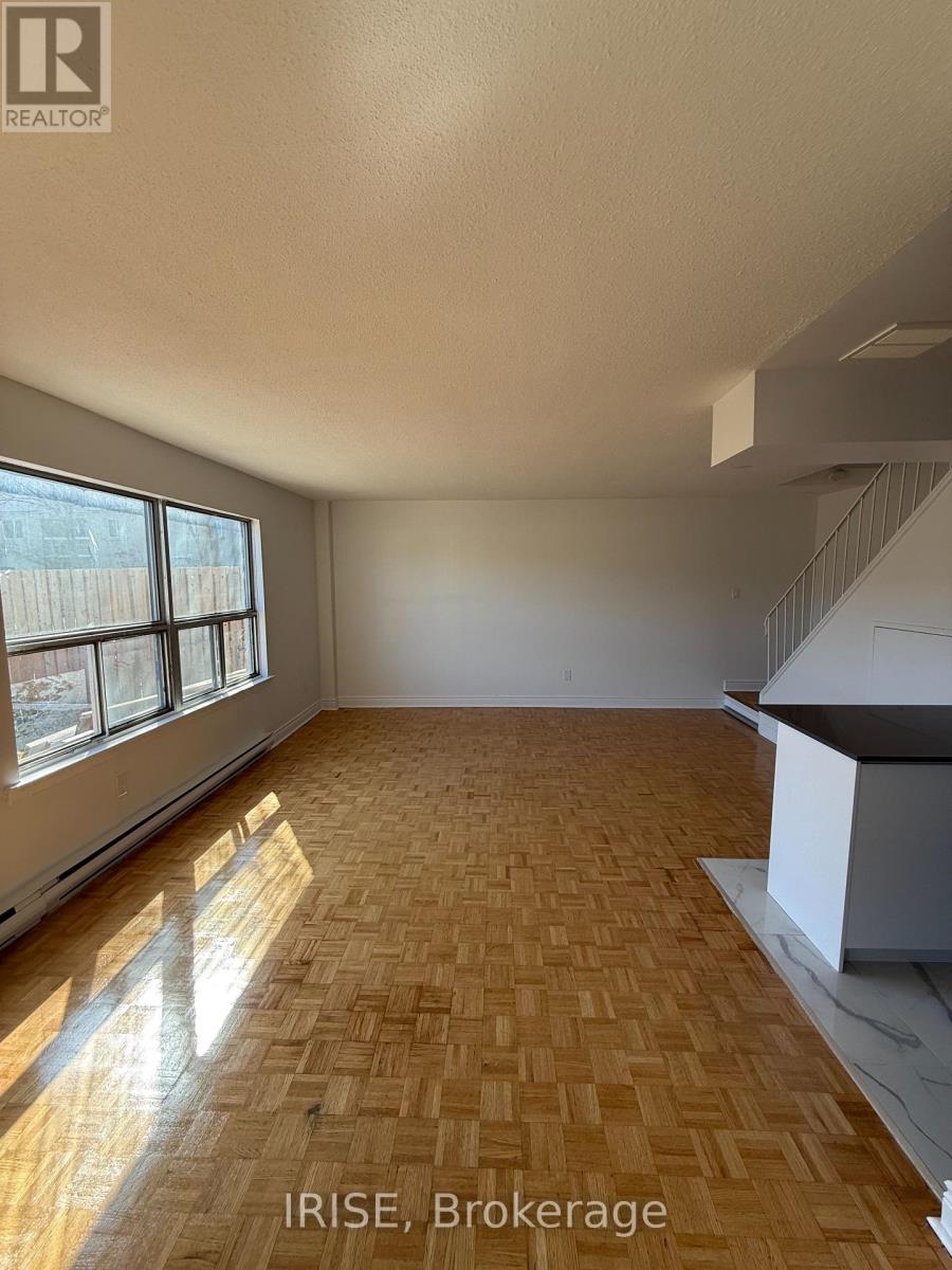 A room with wooden flooring and a window letting in sunlight.