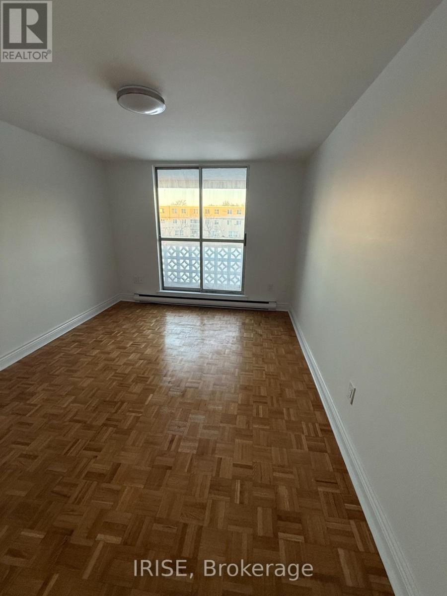 A room with wooden flooring and a window showing a view of a building.