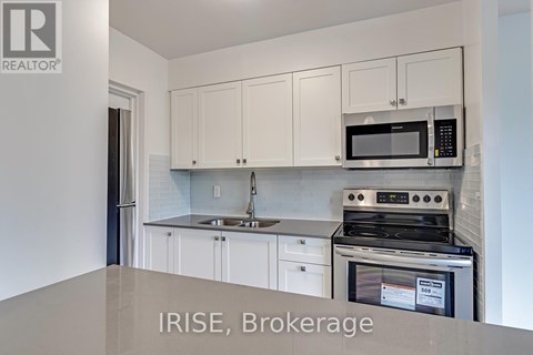 A kitchen with white cabinets and a stove top oven.