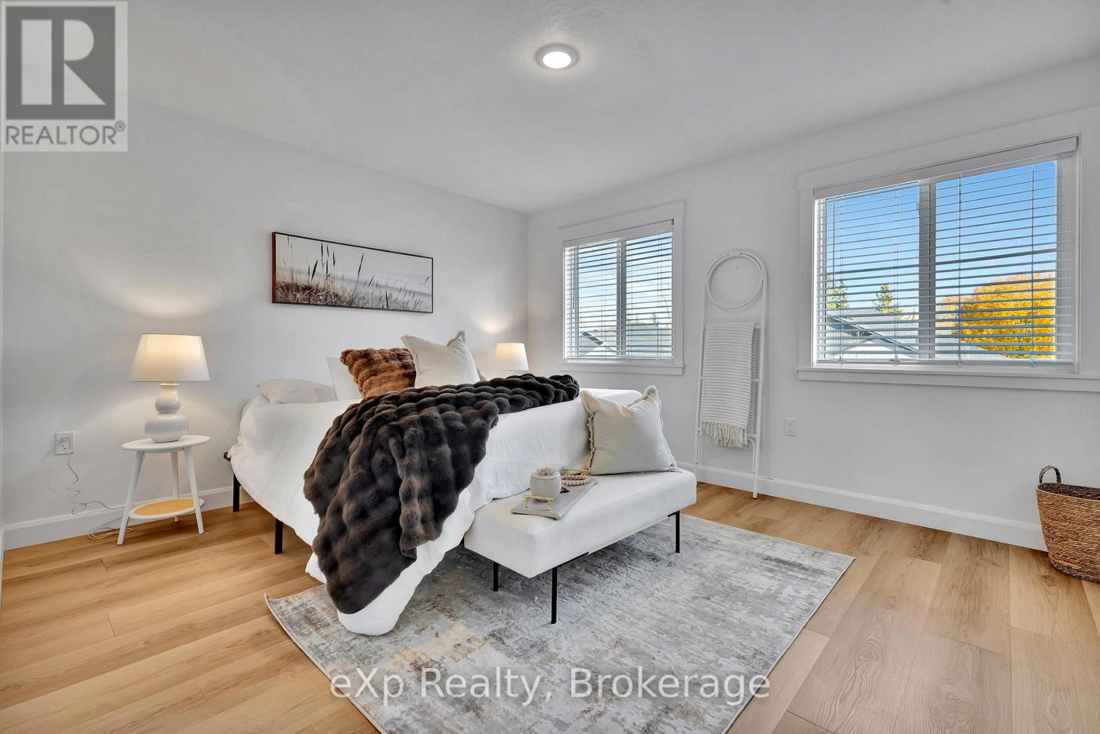 A living room with a white couch and a painting on the wall.