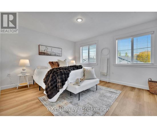 A living room with a white couch and a painting on the wall.