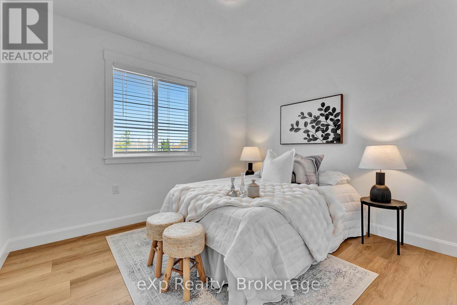 A bedroom with a bed, two lamps, and a painting on the wall.