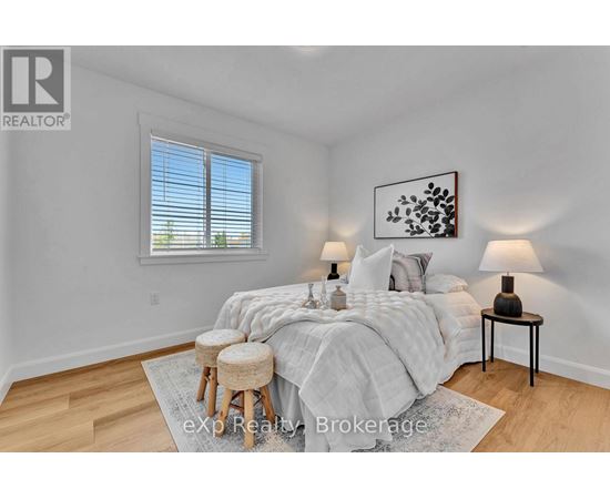 A bedroom with a bed, two lamps, and a painting on the wall.