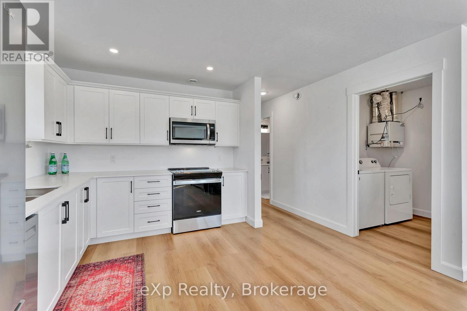 A kitchen with white cabinets and a red rug on the floor.