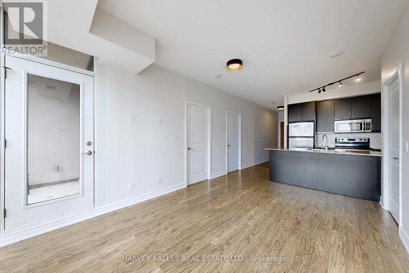 A spacious kitchen with white cabinets and a wooden floor.