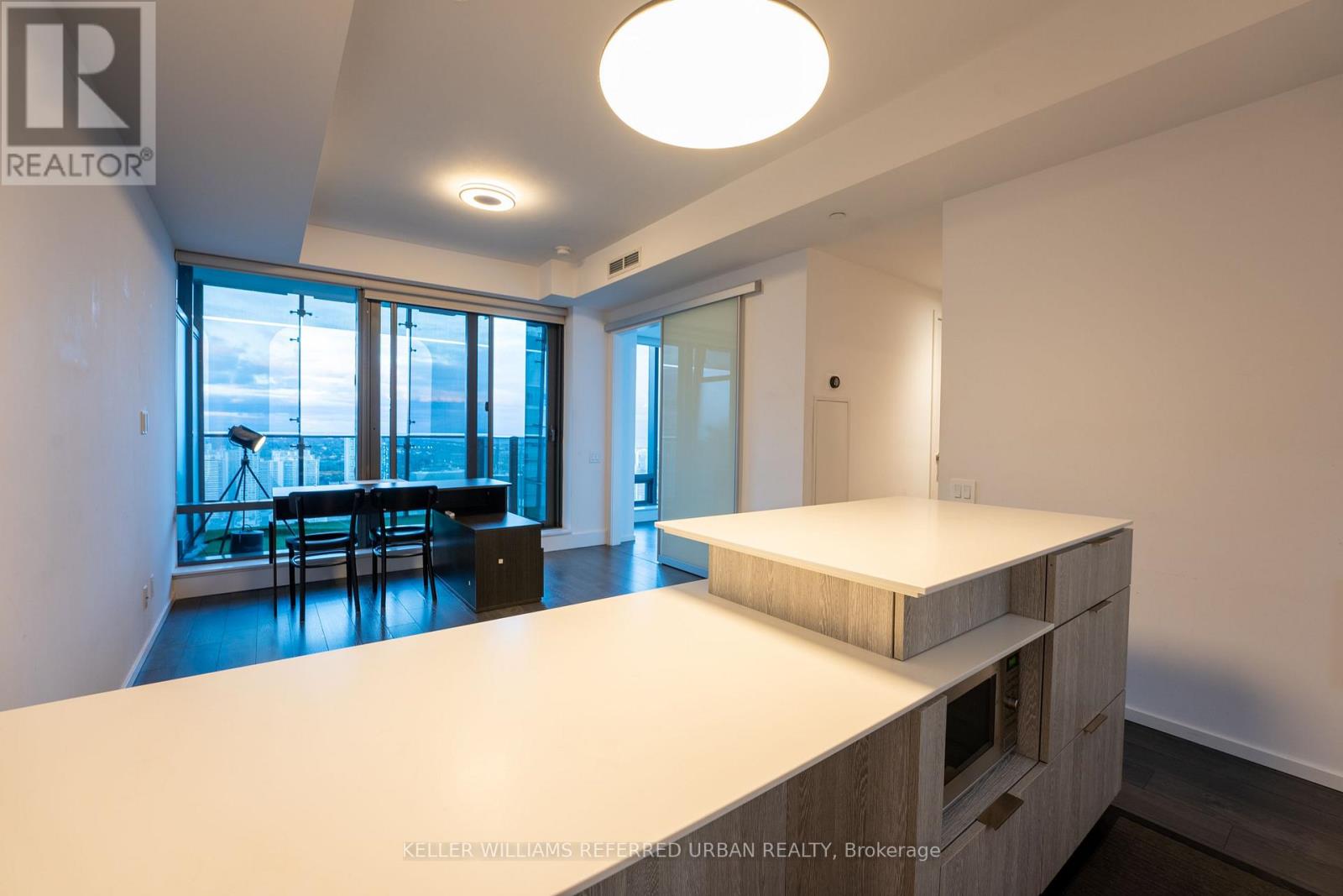 A well-lit, empty room with a large window and a kitchen island.