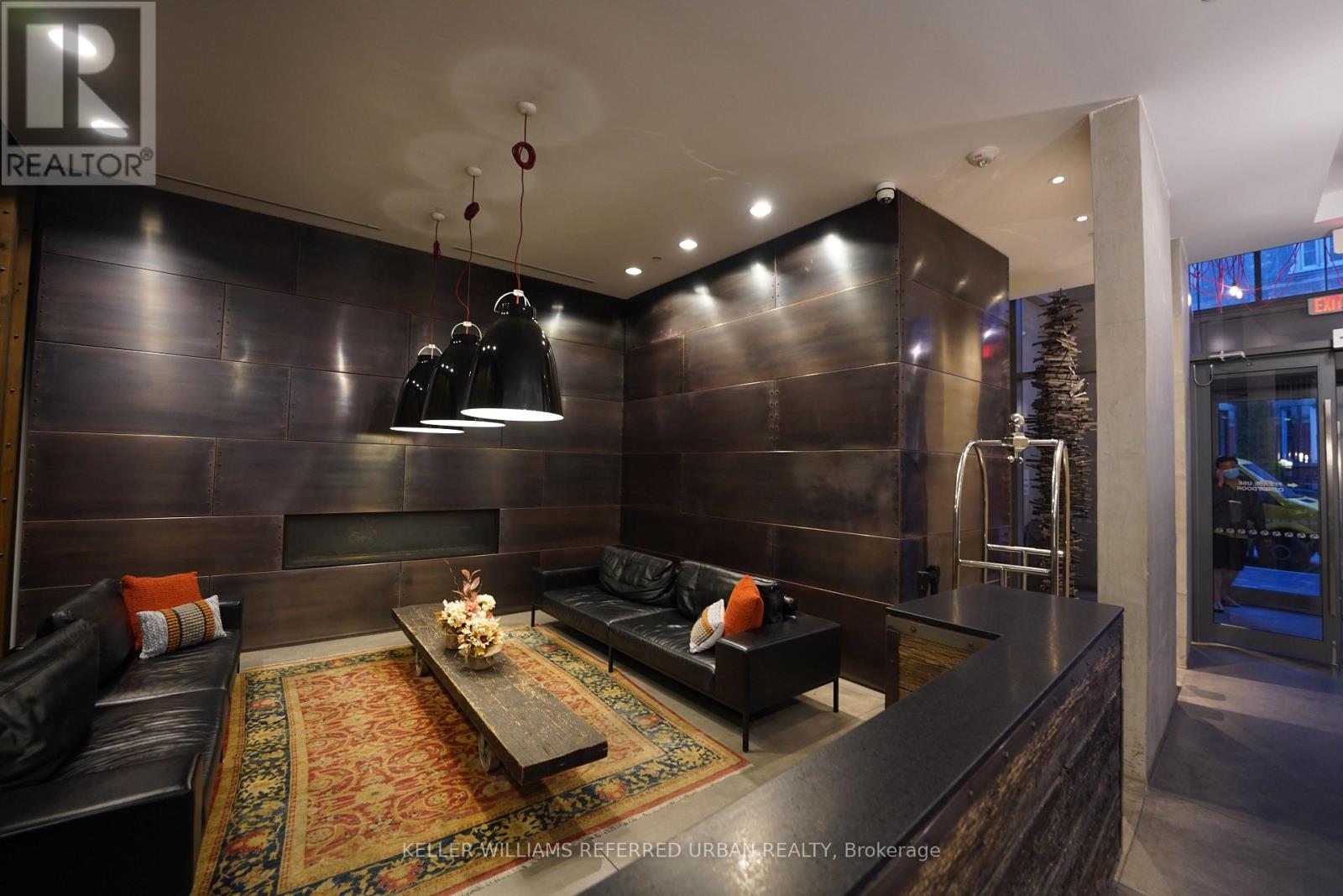 A modern living room with a dark wood floor and a large black couch.