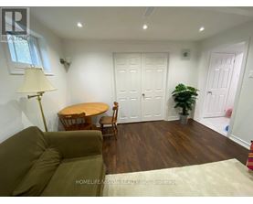 A living room with a brown couch, a round table, and a potted plant.