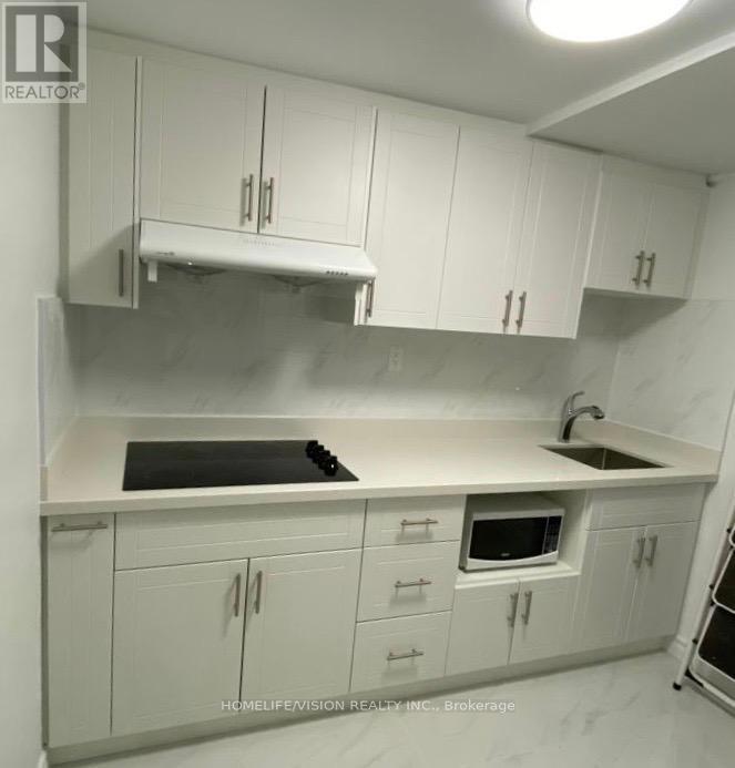 A kitchen with white cabinets and a black stove top.