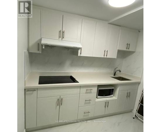 A kitchen with white cabinets and a black stove top.