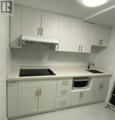 A kitchen with white cabinets and a black stove top.