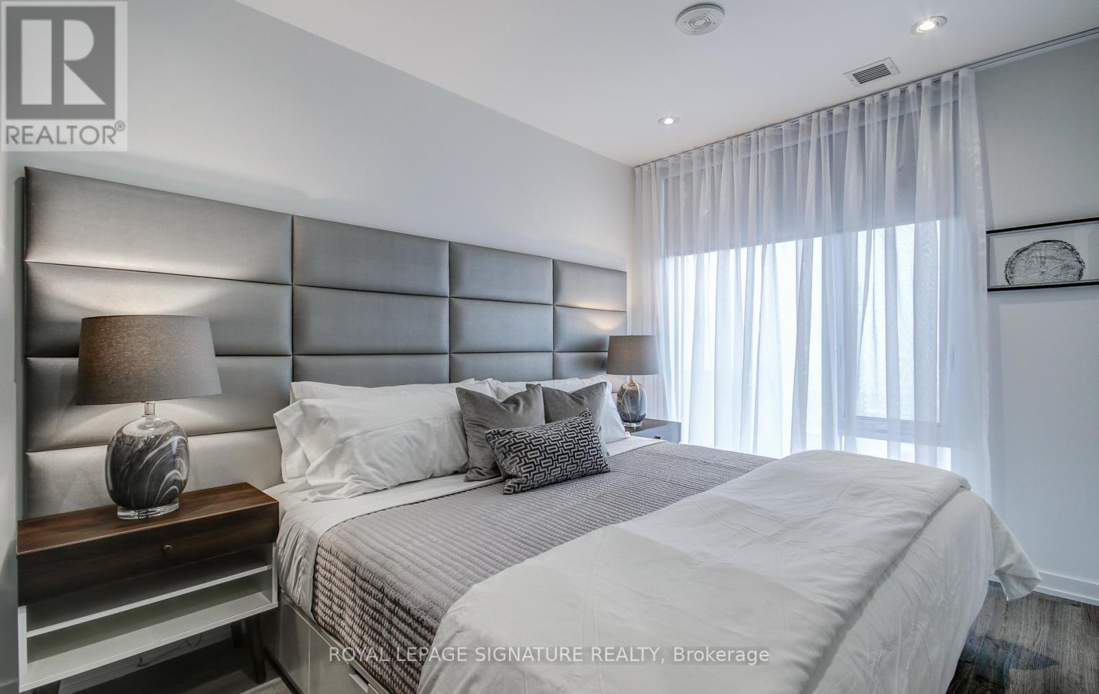 A bedroom with a large bed and a lamp on the side table.