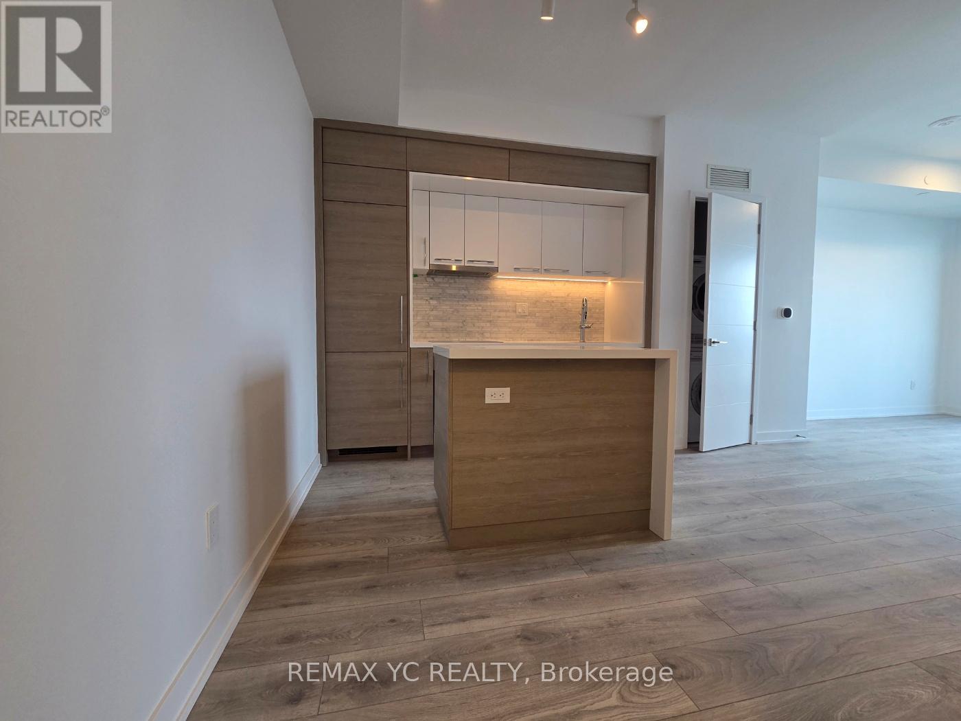 A REALTOR® logo is on the wall above a wooden cabinet with a glass door.