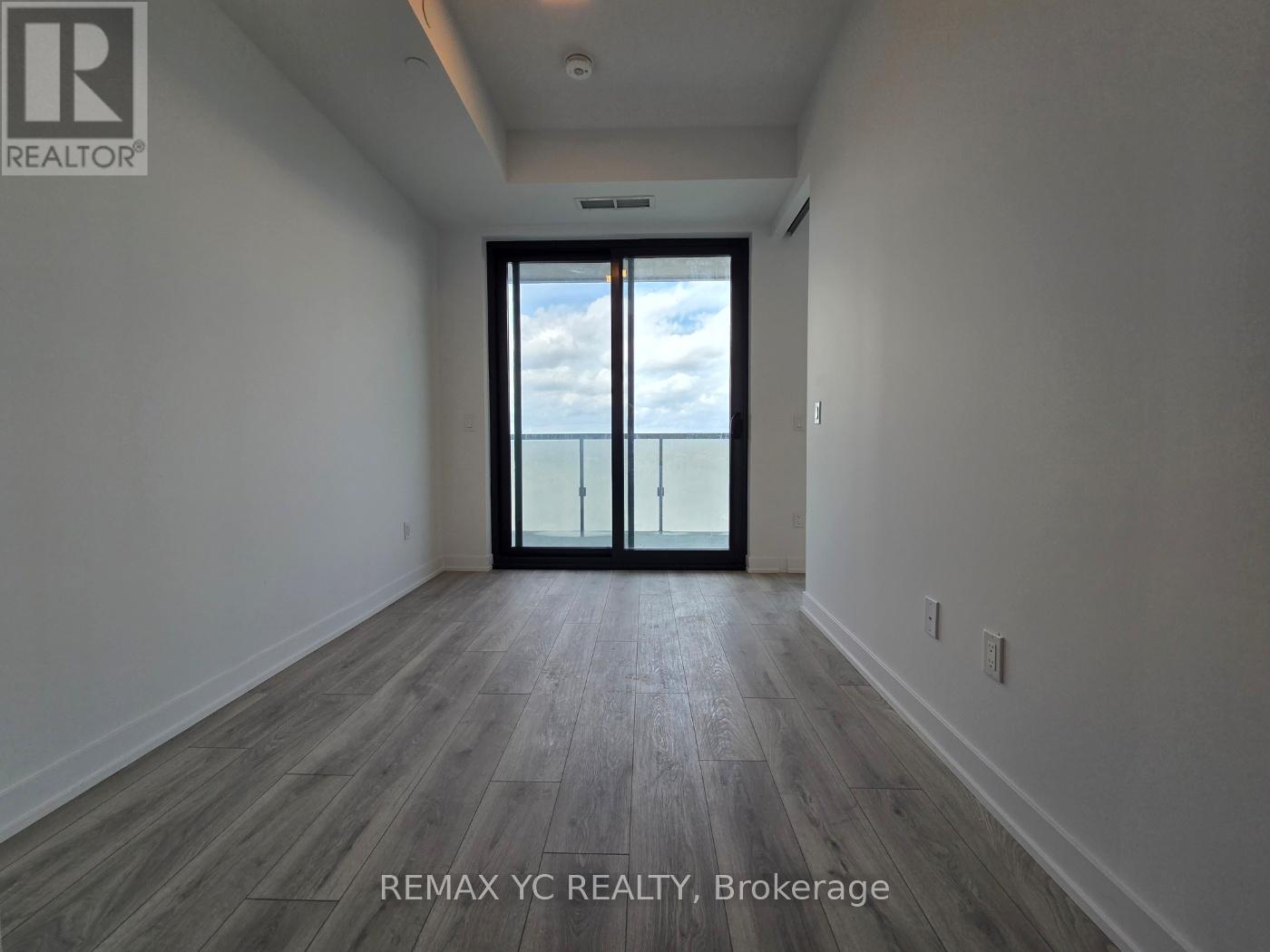 A spacious room with a sliding glass door leading to a balcony.