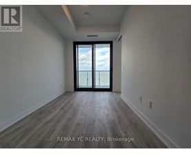 A spacious room with a sliding glass door leading to a balcony.