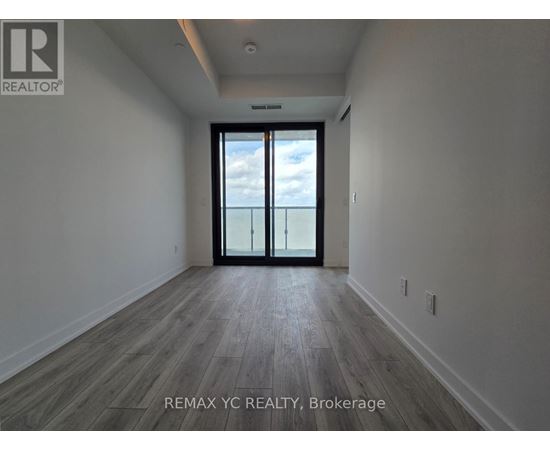 A spacious room with a sliding glass door leading to a balcony.