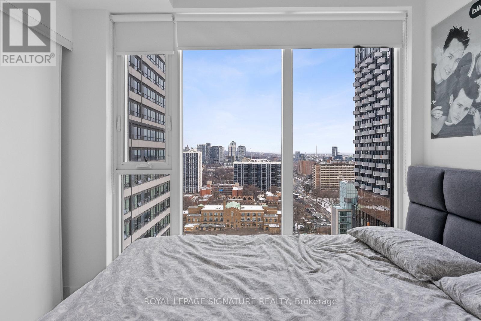 A bedroom with a large bed and a window overlooking a cityscape.