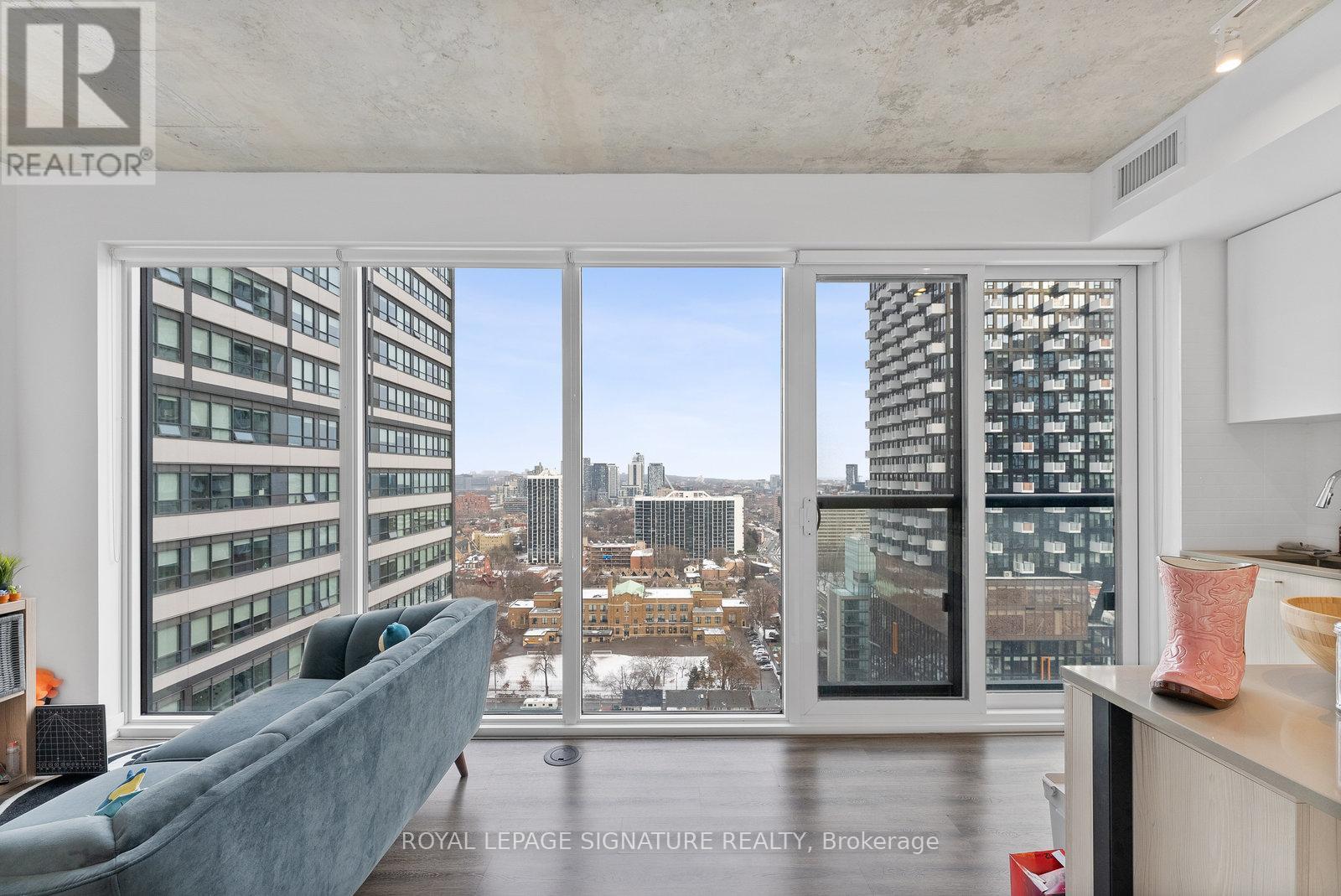 A living room with a grey couch and a view of the city.