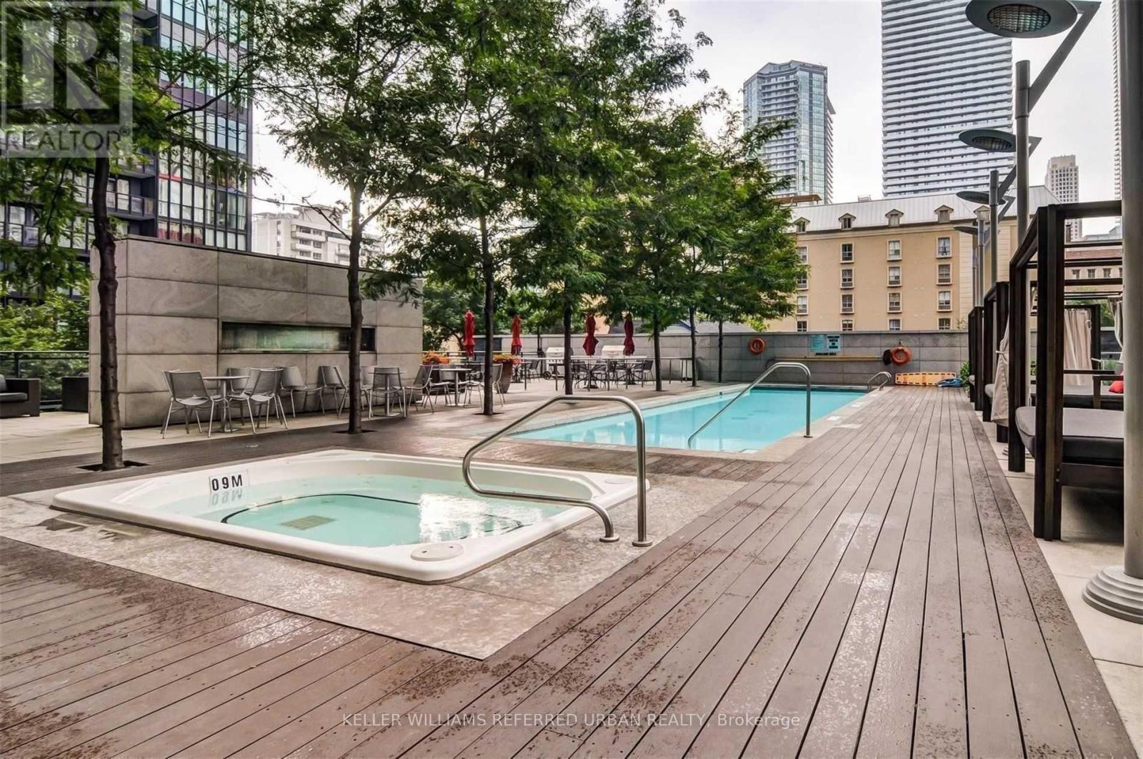 A wooden deck with a pool in the middle and trees on the side.