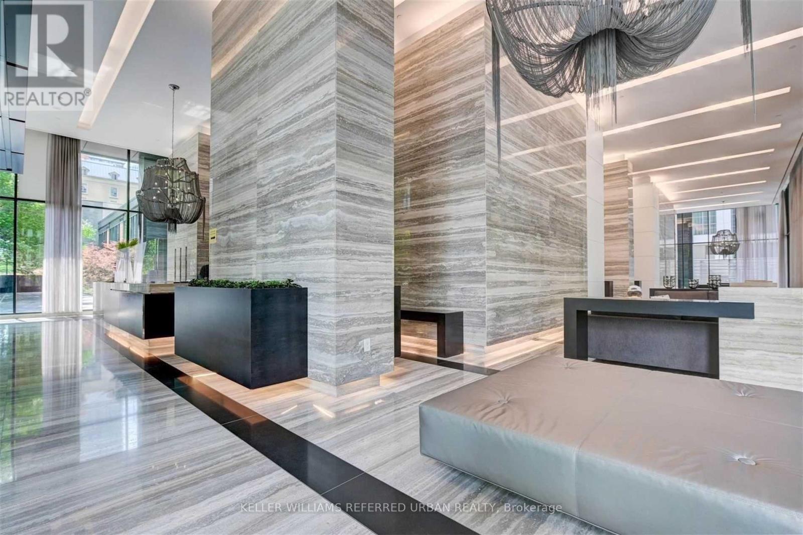 A modern bedroom with a large bed and a stone column.