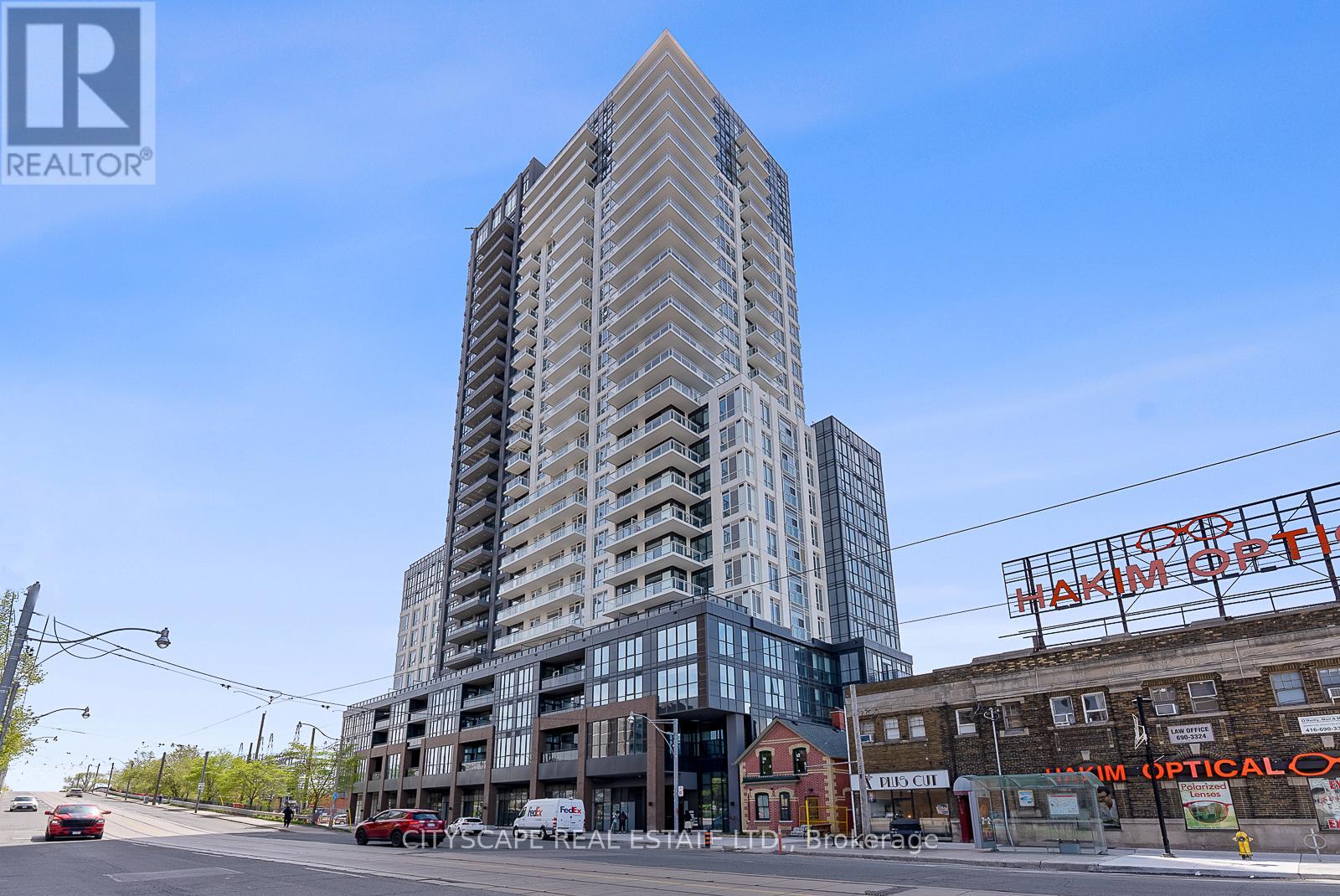 A tall building with a glass facade stands in the middle of a street.