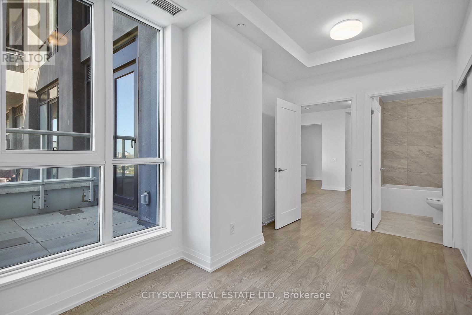 A spacious, well-lit room with a large window and a door leading to another room.