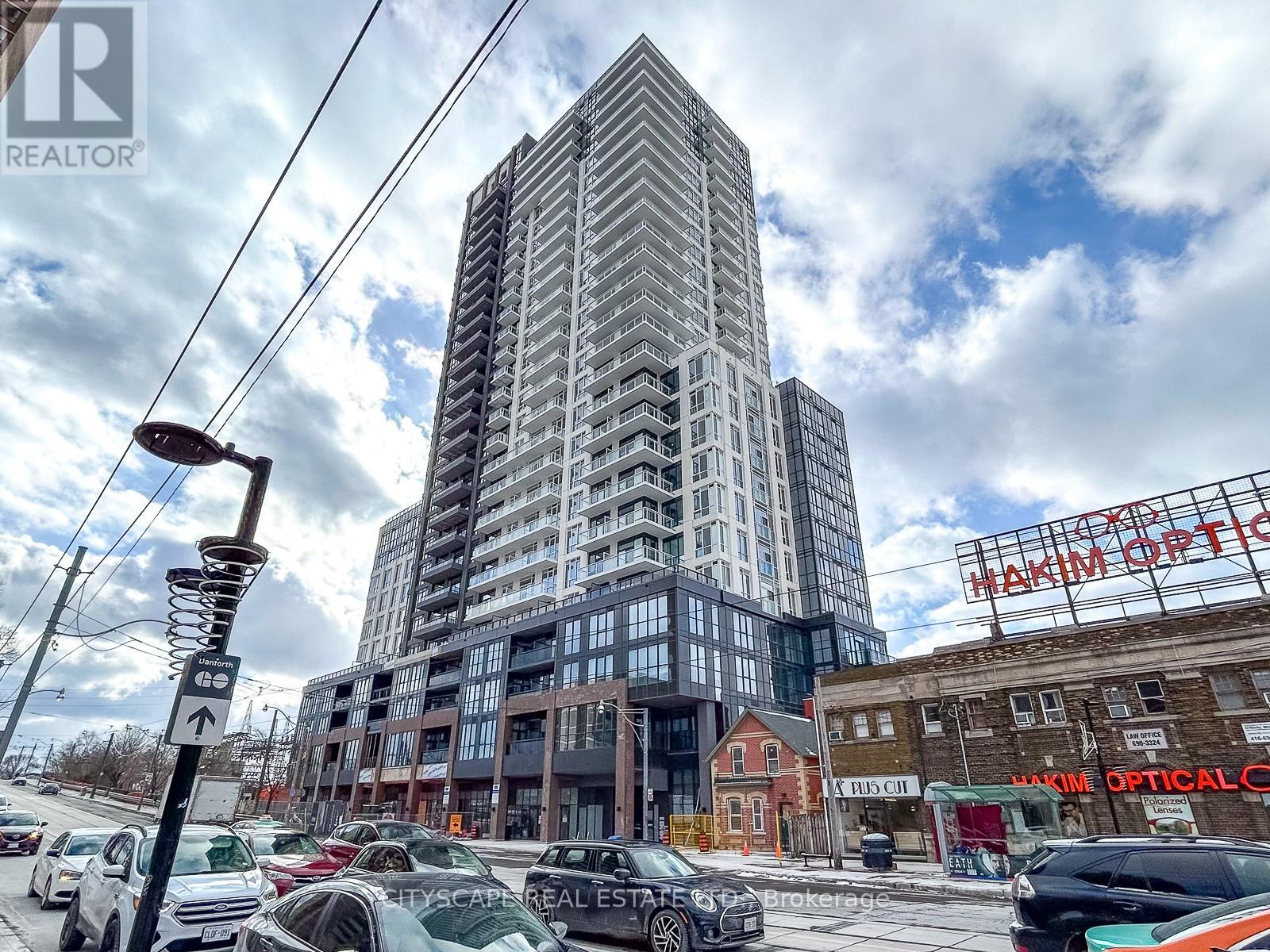 A tall building with many windows is in the background of a busy street.