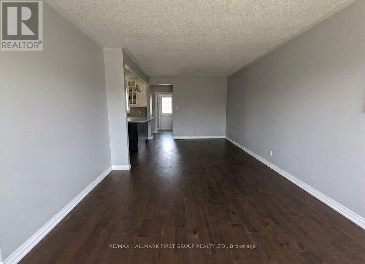 A long, empty hallway with wood floors and white walls.