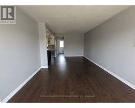 A long, empty hallway with wood floors and white walls.