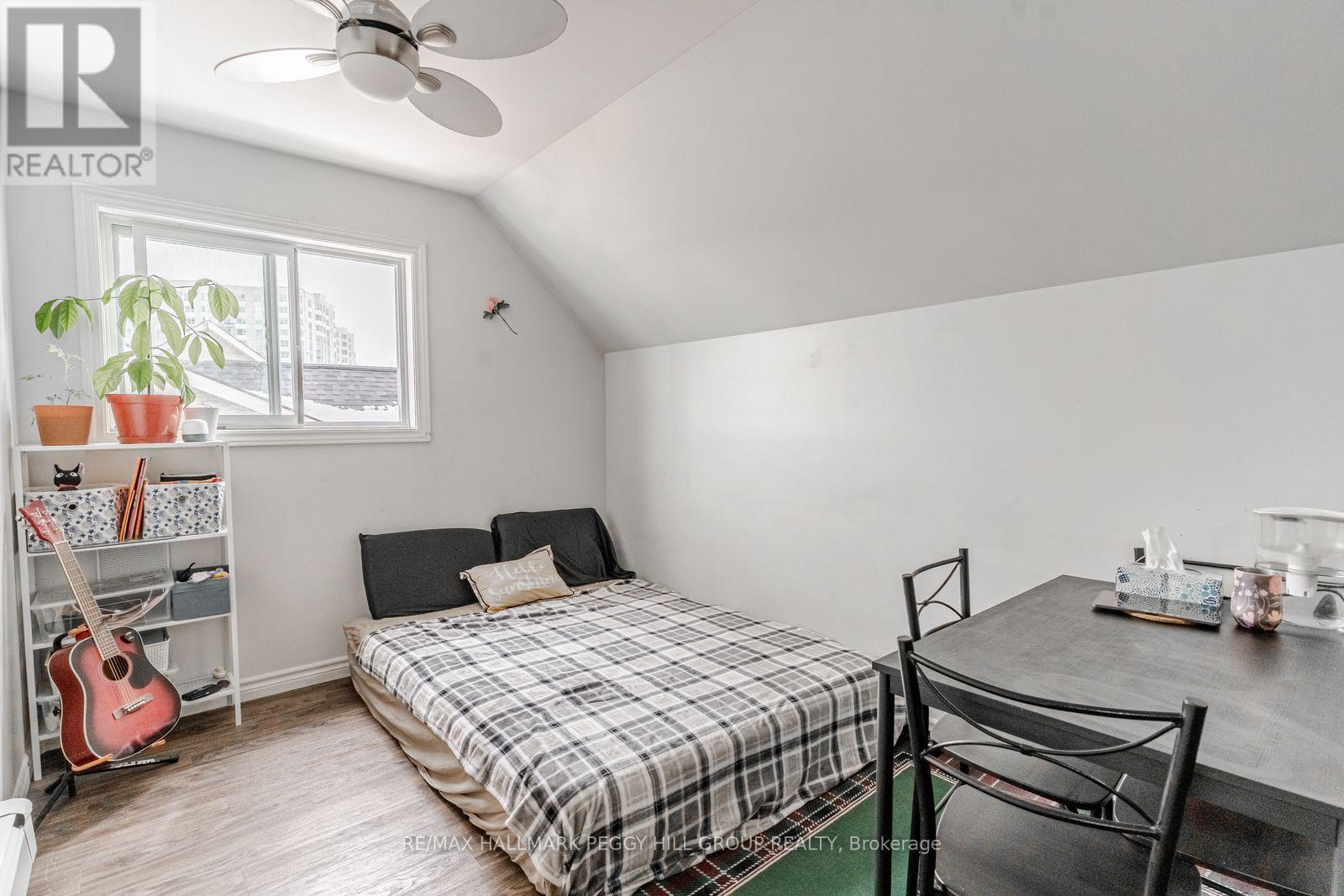A bedroom with a bed, a guitar, a chair, and a plant.