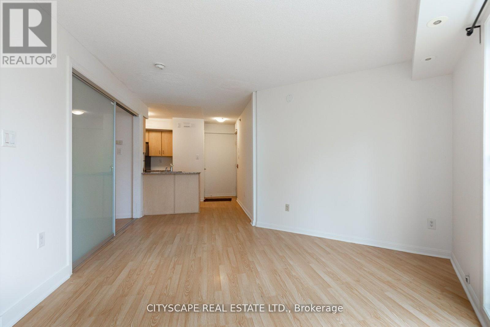 A spacious room with wooden flooring and white walls.
