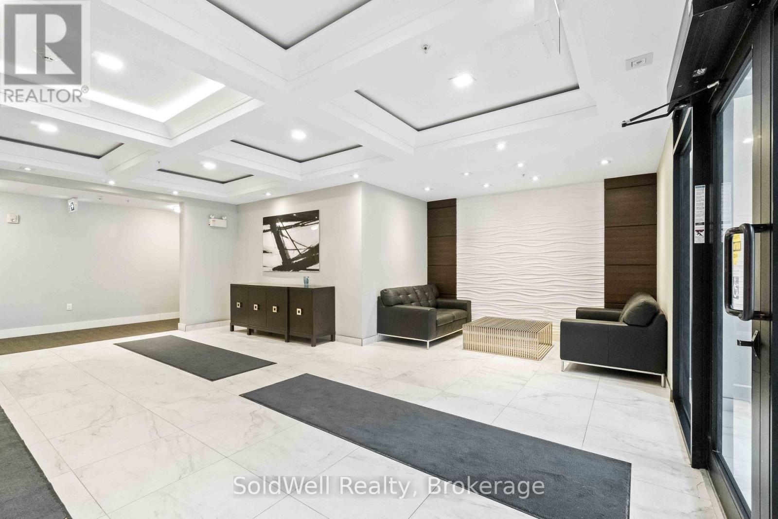 A spacious room with a black and white marble floor, a black sofa, and a wooden cabinet.