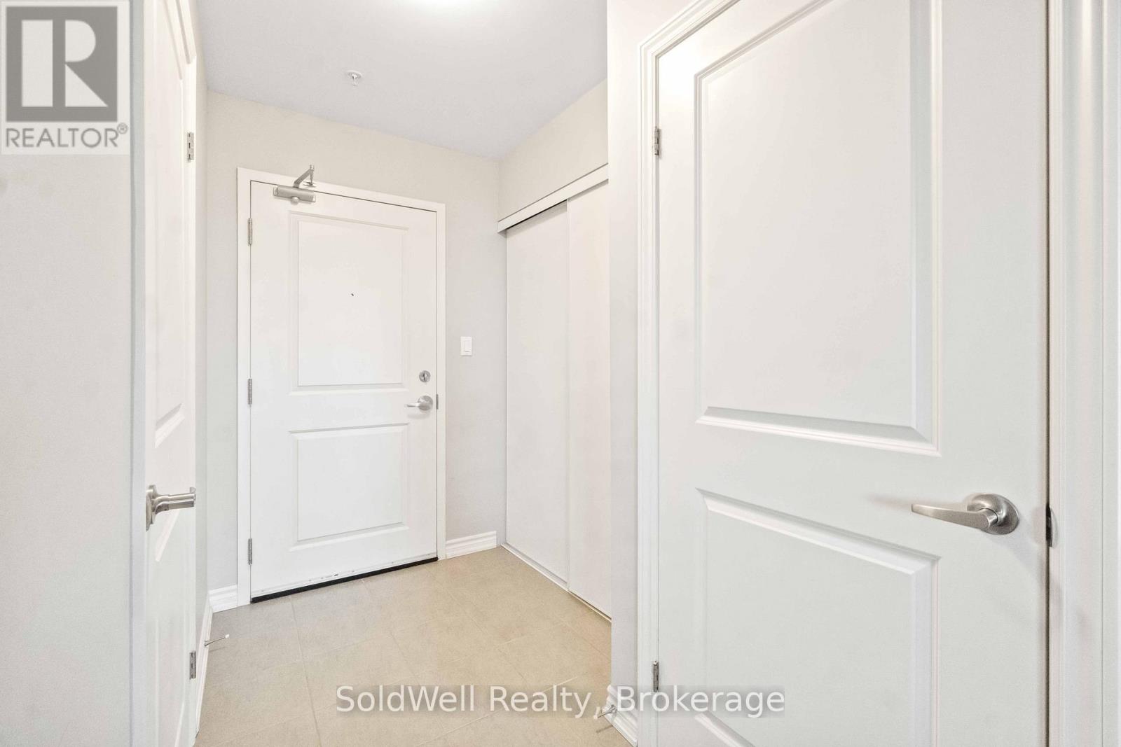 A hallway with two doors and a brokerage logo.