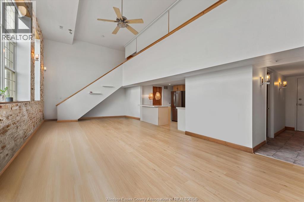 A spacious room with wooden floors and a staircase leading to the upper level.