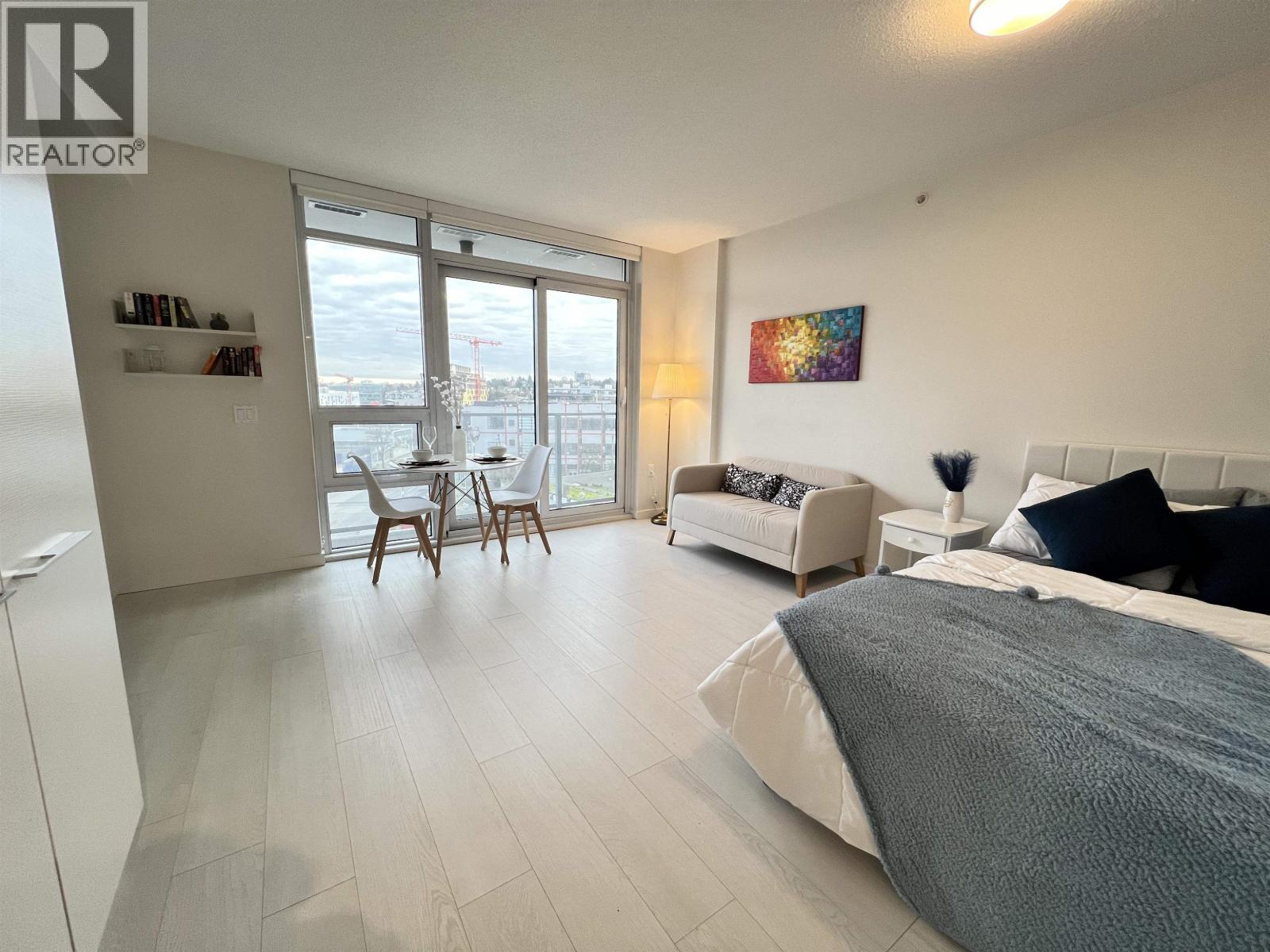 A bedroom with a large bed and a balcony with chairs.