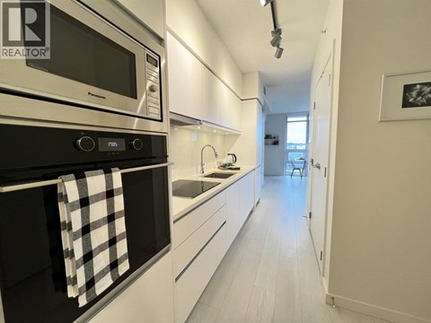 A modern kitchen with white cabinets and a black oven.