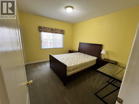 A bedroom with a bed, nightstand, and window.