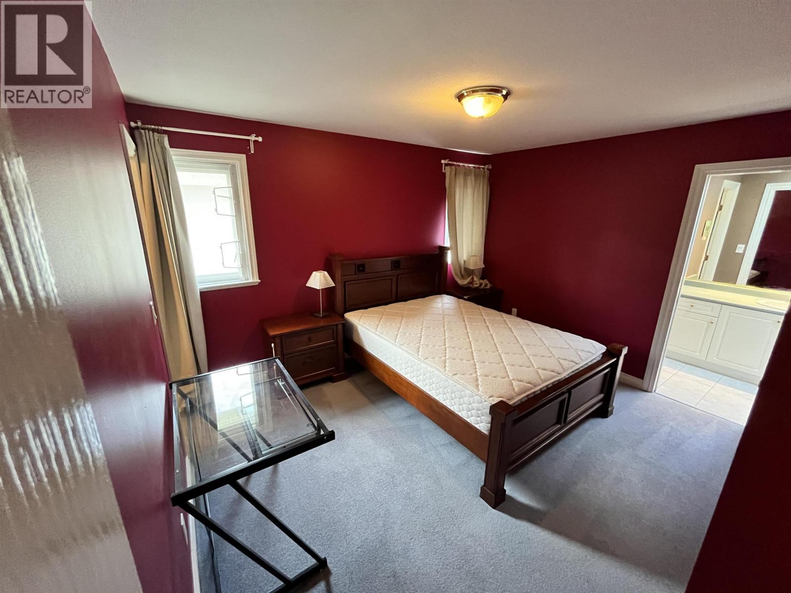 A bedroom with a bed, nightstand, and window.