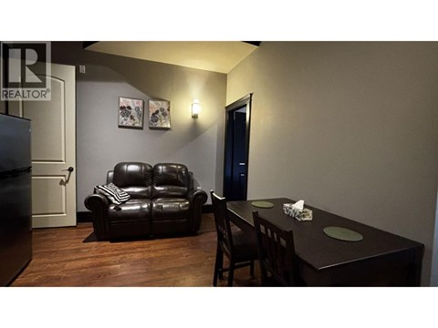 A black leather sofa sits in a living room with a wooden table and chairs.