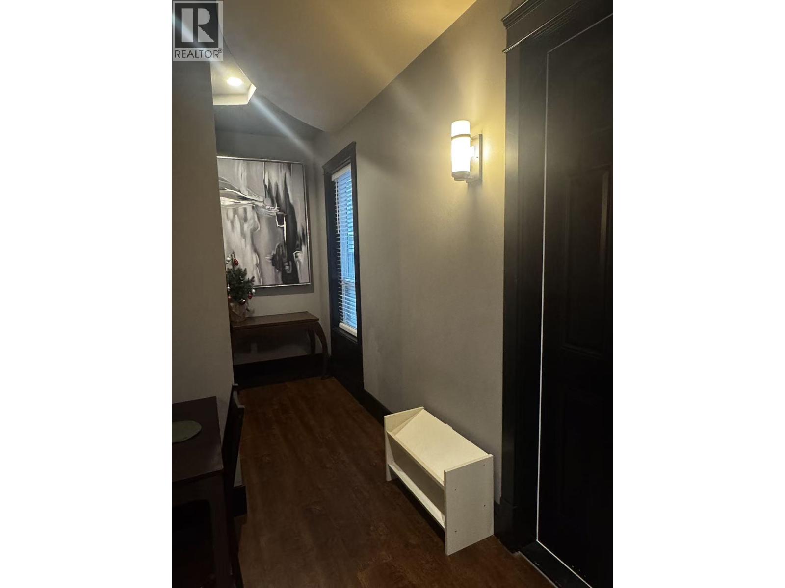 A hallway with a bench and a realtor sign.