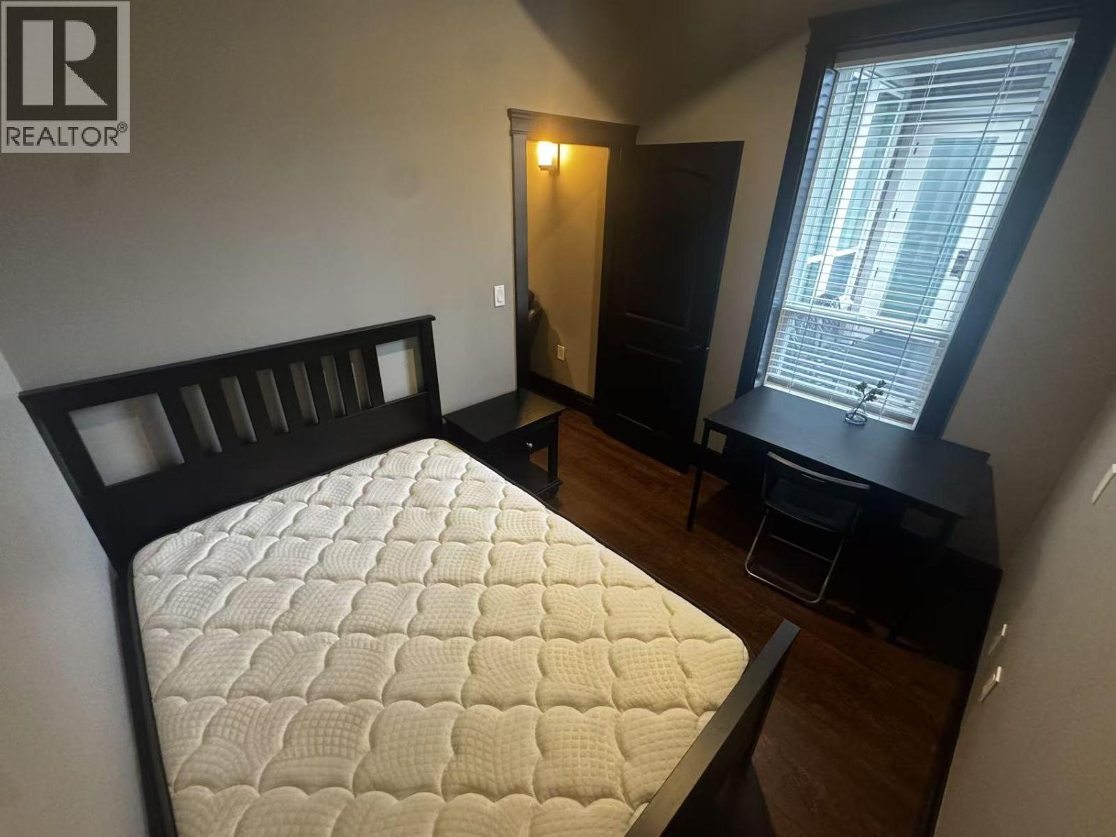 A bedroom with a bed, desk, and chair.