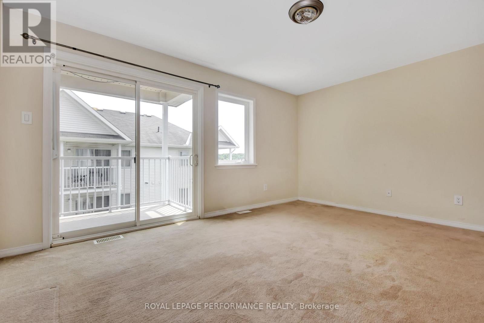 A spacious room with a sliding glass door leading to a balcony.