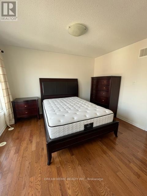 A bedroom with a large bed and wooden floors.