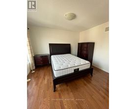 A bedroom with a large bed and wooden floors.